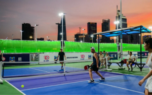Sân pickleball ngoài trời được chiếu sáng bằng đèn LED vào buổi tối với người chơi thi đấu